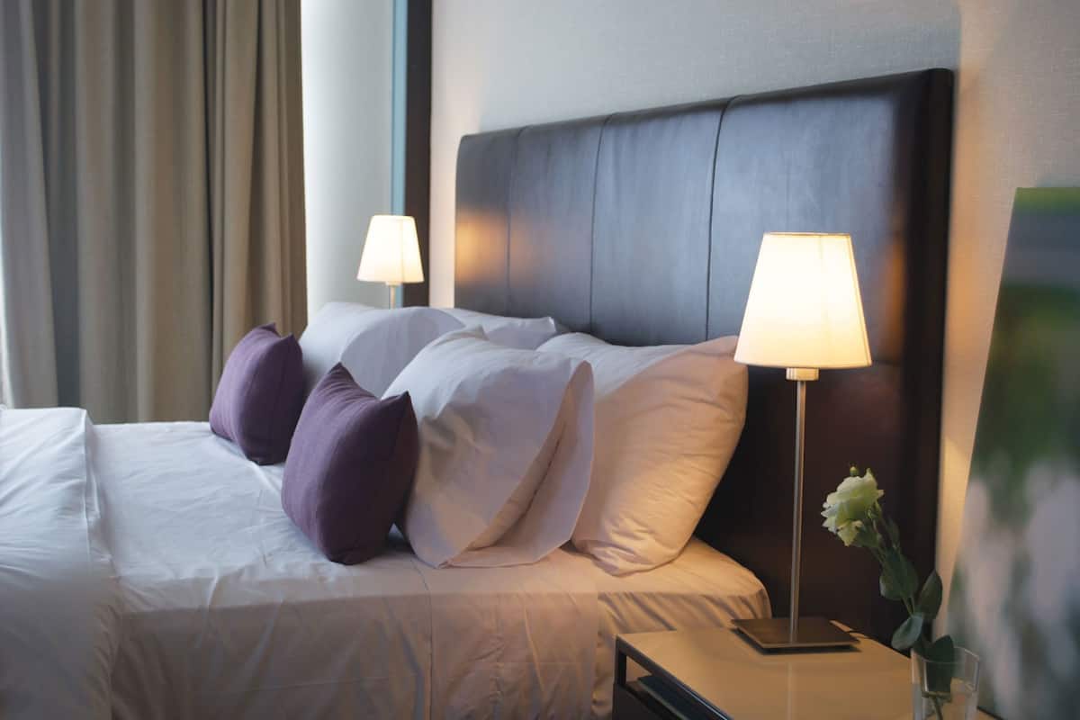 Ein Hotelzimmer mit einem Bett, zwei Nachttischlampen und einer Blumenvase.