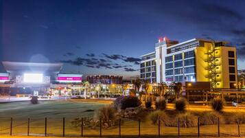 A modern hotel with a prominent entrance, a well-lit parking area, and a landscaped courtyard.