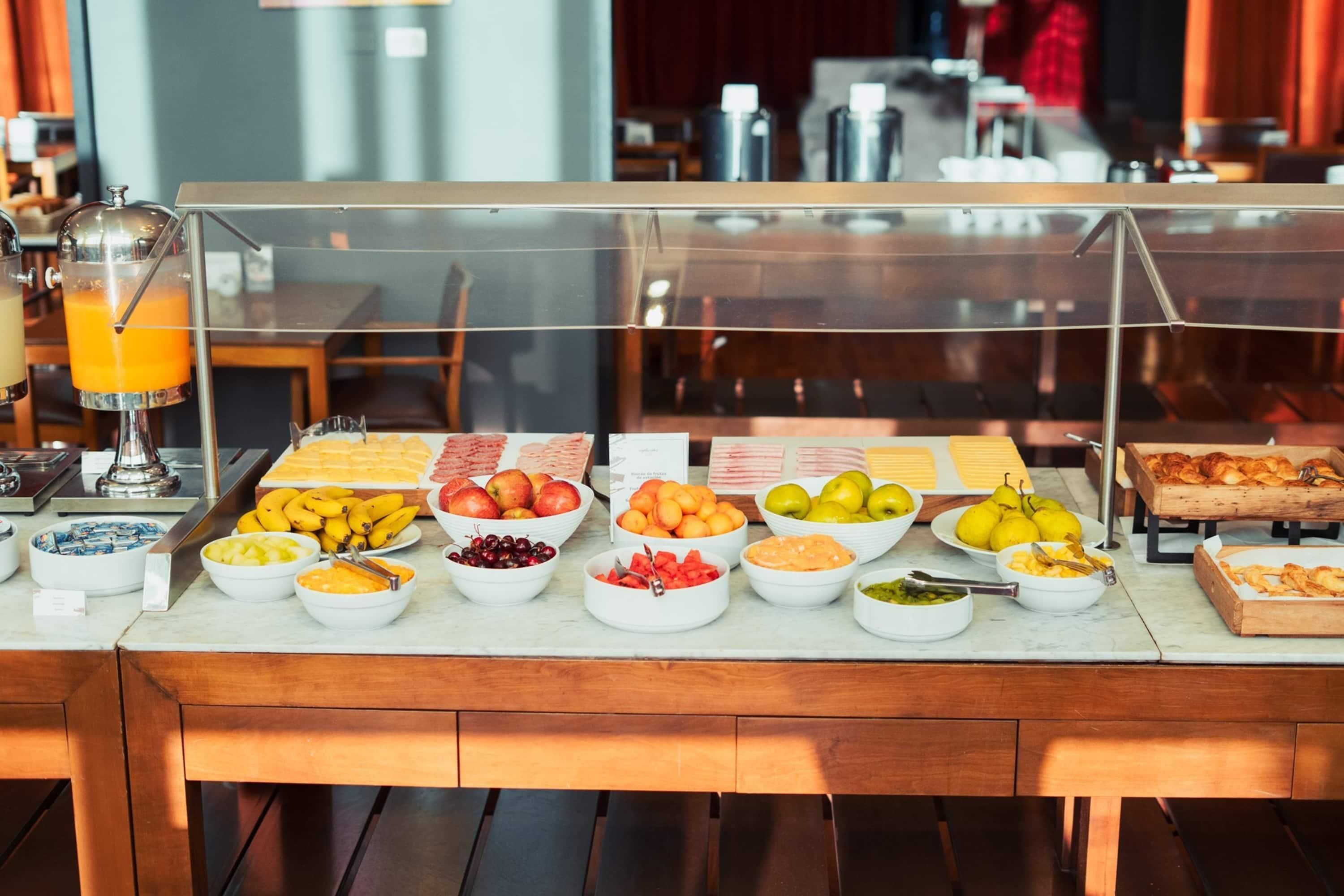 Un buffet proposant une variété de fruits et un distributeur de jus.
