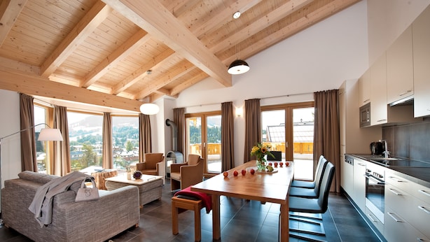 Ein modernes Wohnzimmer mit einer Couch, einem Esstisch und einer Küchenzeile.