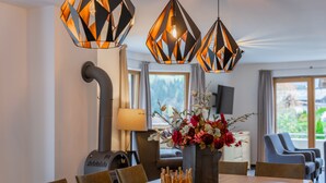 Ein Essbereich mit einem Holztisch, Stühlen, einer Blumenvase und geometrischen Pendelleuchten.
