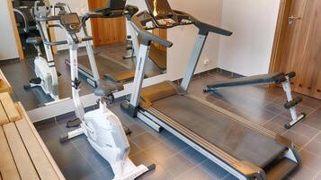 A gym with treadmills, elliptical machines, and a bench.