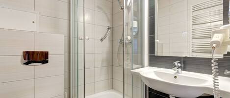 A modern bathroom with a glass-enclosed shower, a white sink, and a mirror above the sink.