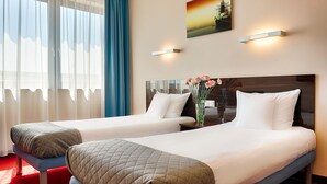 A hotel room with two beds, a large window with curtains, a painting on the wall, and a vase with flowers on the nightstand. - Hotel Focus Gdansk (Gdansk)