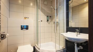 Un baño moderno con ducha de vidrio, un lavamanos blanco y un inodoro.