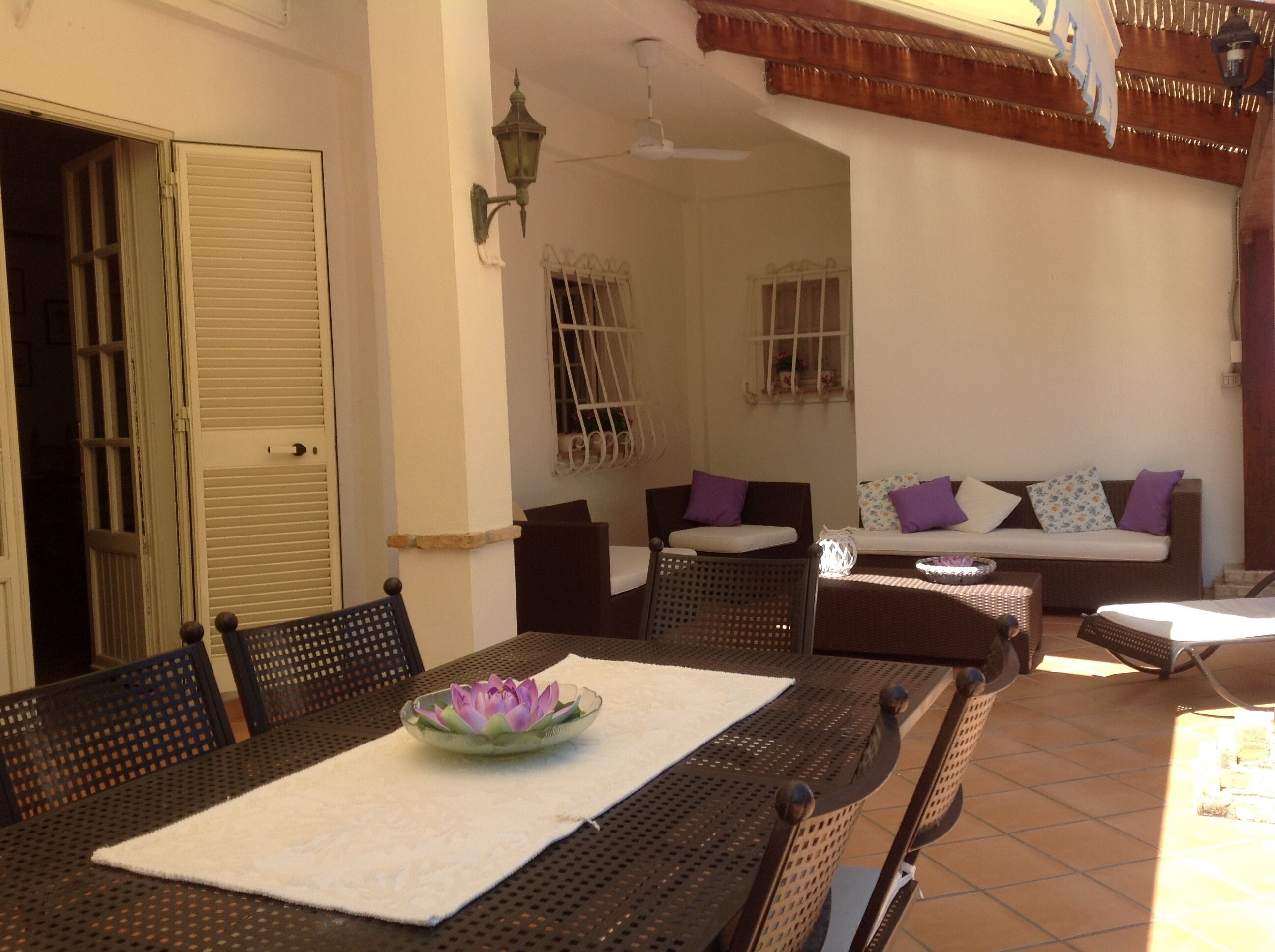 A dining area with a table set for two, a sofa with cushions, and a decorative bowl on the table.