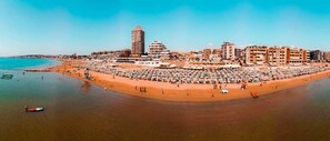 A coastal cityscape with a wide beach, numerous buildings, and a clear sky. - Hotel Scacciapensieri (Nettuno)