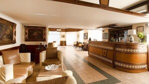 Un hall d’hôtel avec des canapés en cuir, un comptoir d’accueil et des œuvres d’art encadrées accrochées aux murs.