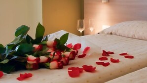 Une chambre d’hôtel avec un lit, une table de chevet sur laquelle se trouve un verre à vin, et un luminaire fixé au mur.