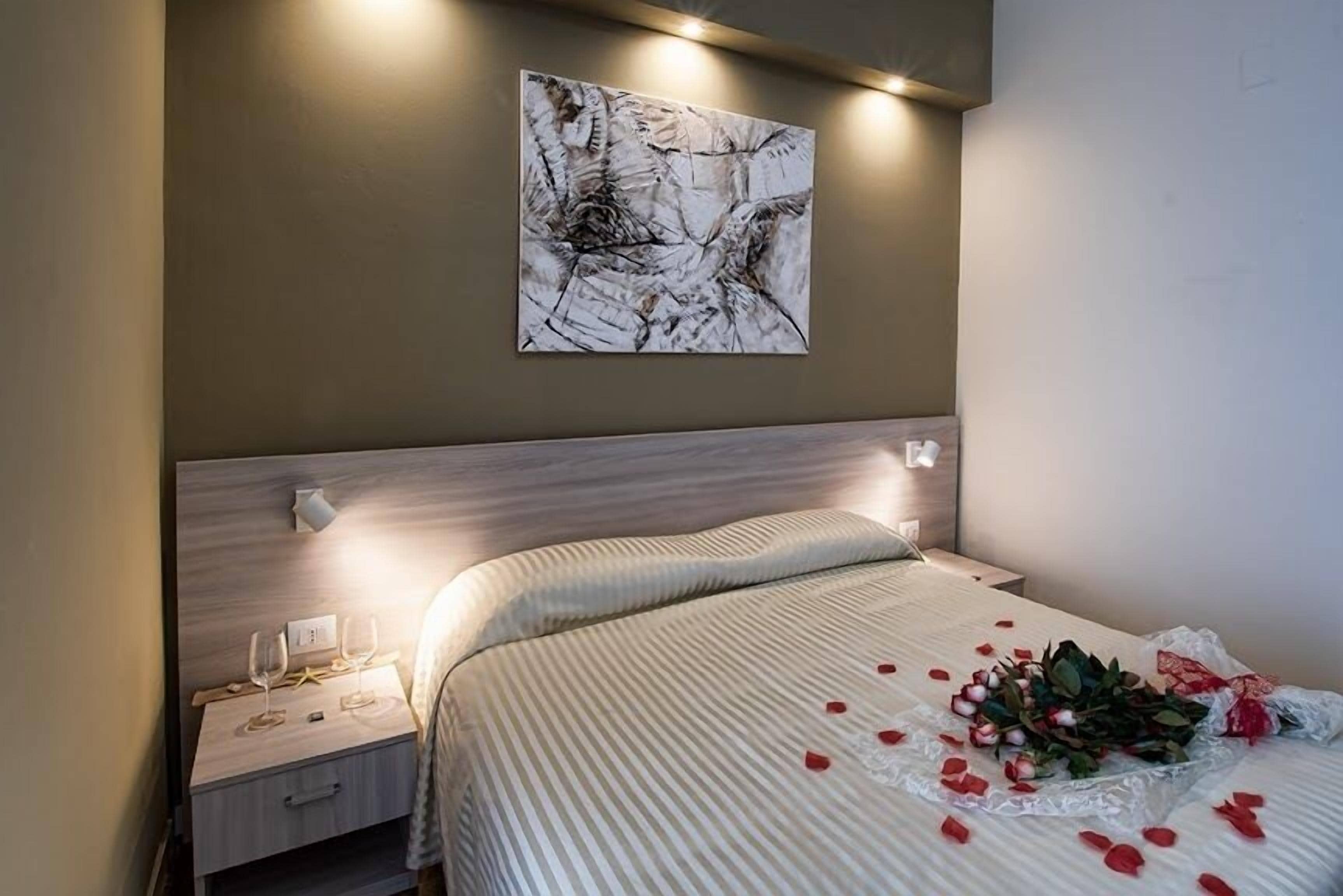 A hotel room with a bed, bedside table, and a wall-mounted artwork.