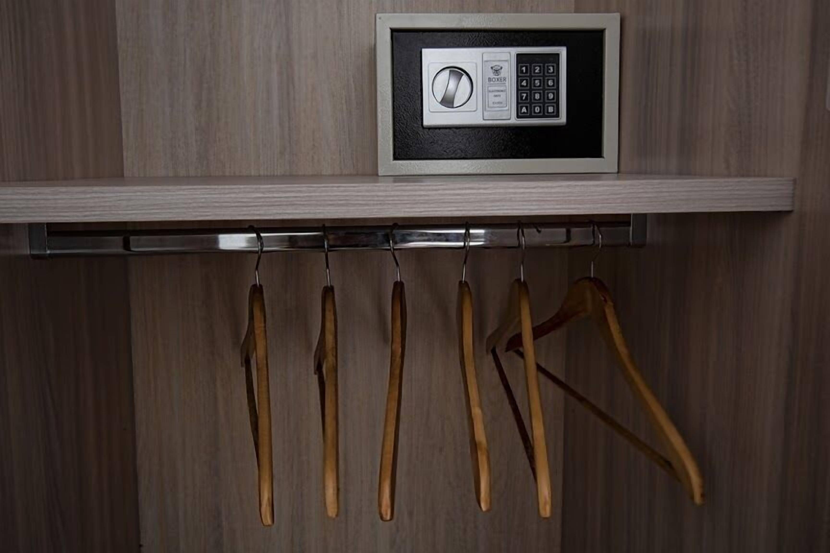 A wooden wardrobe with a built-in microwave and a metal hanger bar.