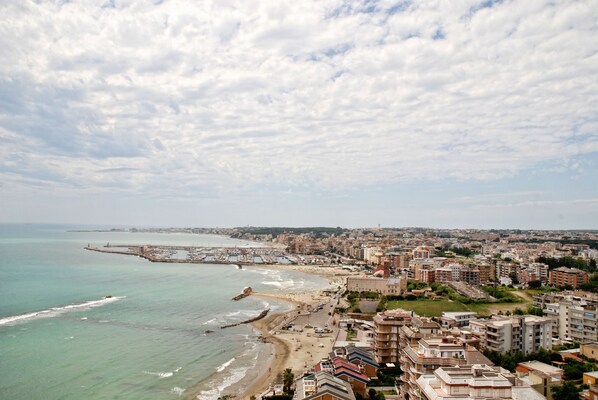 Un paisaje urbano costero con playa, edificios y un muelle.
