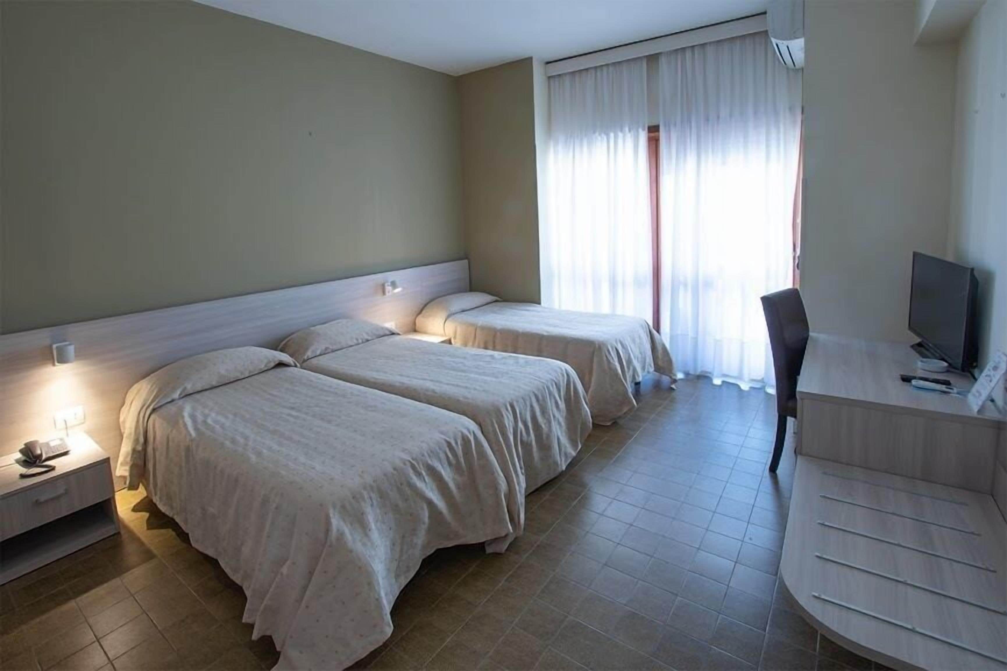 Una habitación de hotel con dos camas, un escritorio, una silla y un televisor.