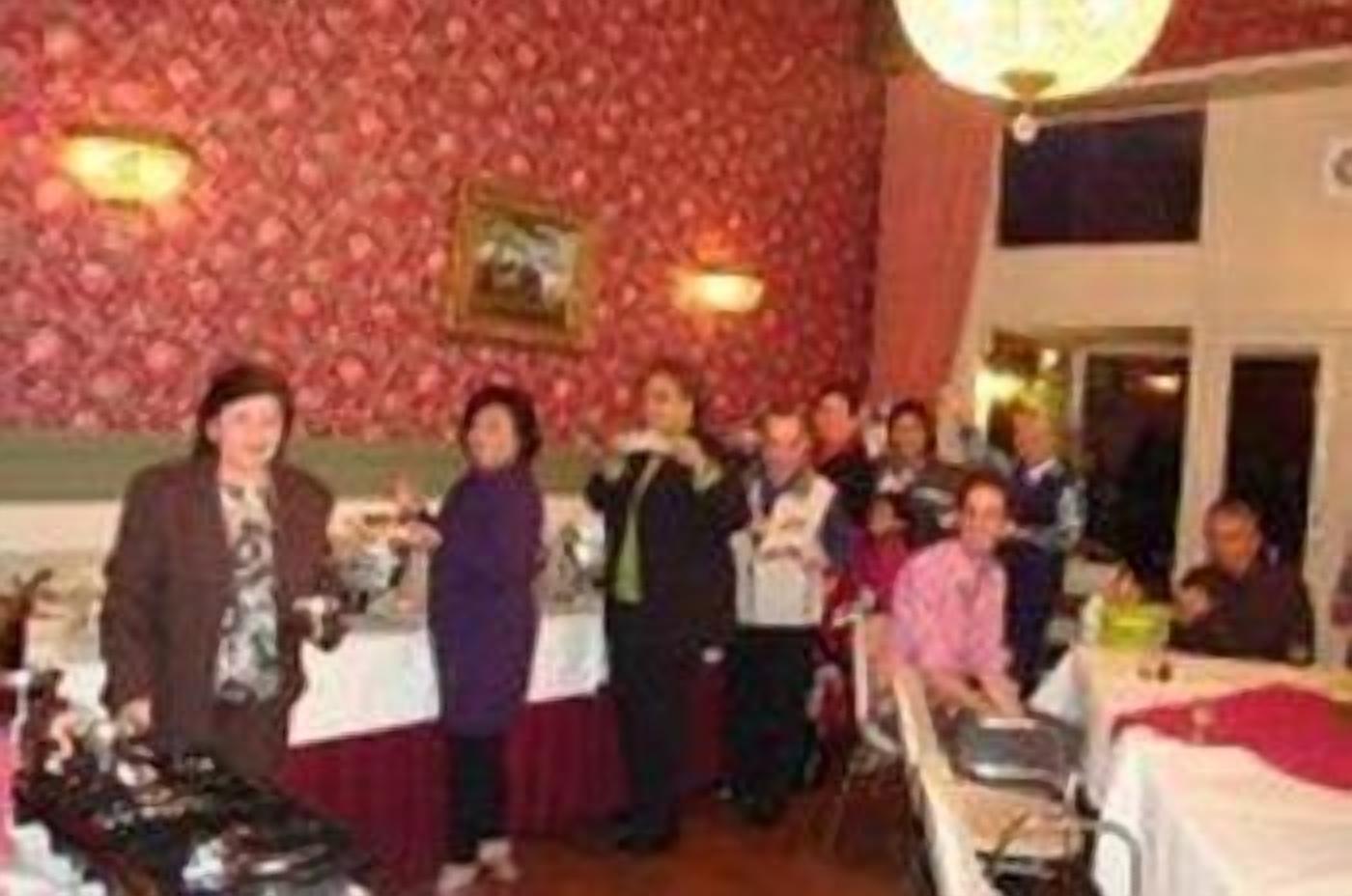 Eine Gruppe von Personen in einem Essbereich mit einer gemusterten Wand und einem Chandelier.