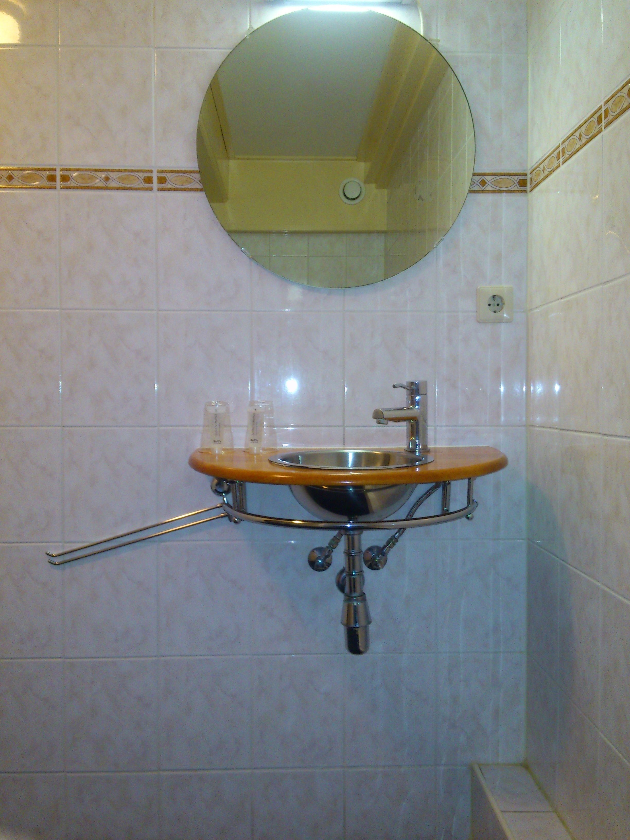 Un baño con lavamanos, espejo y toallero.