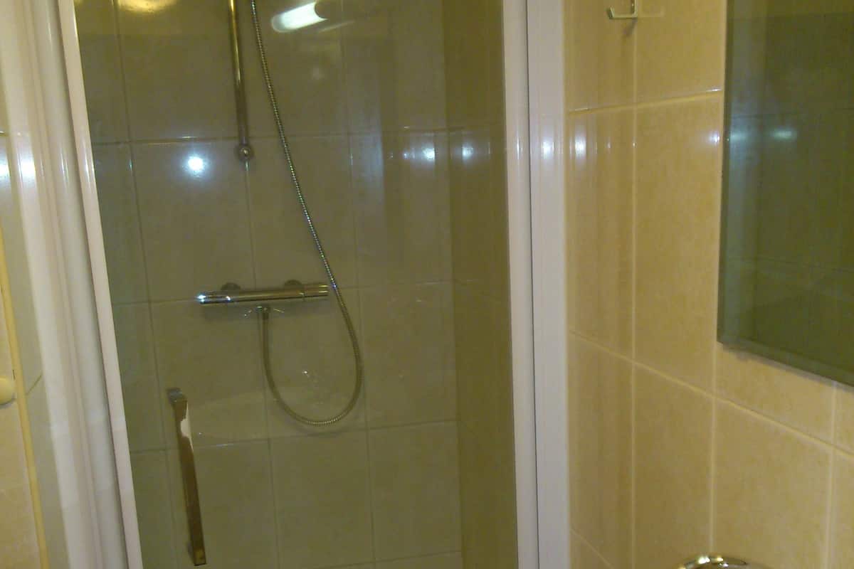 A bathroom with a glass-enclosed shower, a white sink, and a mirror above the sink.