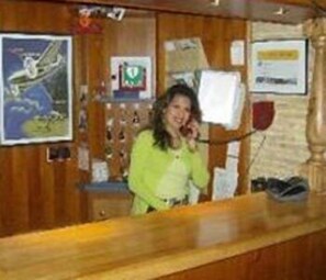 A reception desk with a wooden finish, a framed picture of a bird, and a bulletin board with papers. - Hostel Herberg de Esborg (Scheemda)