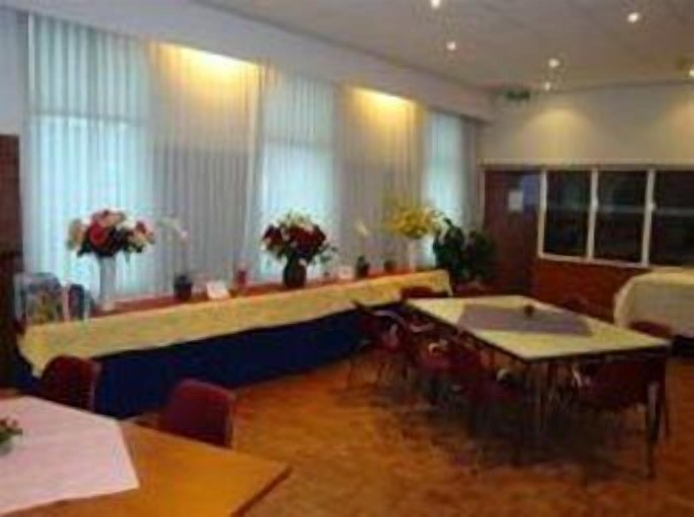 Une salle de conférence avec une longue table, des chaises et des arrangements floraux en guise de décoration.