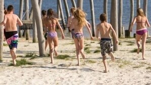 Una playa con estructuras de madera y gente caminando.