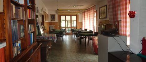 Une bibliothèque avec des étagères, un espace de lecture avec des tables et des chaises, et un coin repas avec des tables et des chaises.