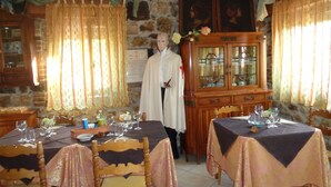 Un comedor con paredes de piedra, muebles de madera y una persona con vestimenta religiosa.