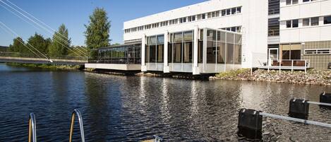 A modern building with large windows overlooking a calm river.