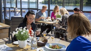 Un grupo de personas cenando en una mesa con vistas a un lago.