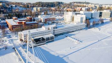 Uma área urbana coberta de neve, com edifícios modernos, uma ponte e uma pista de esqui.
