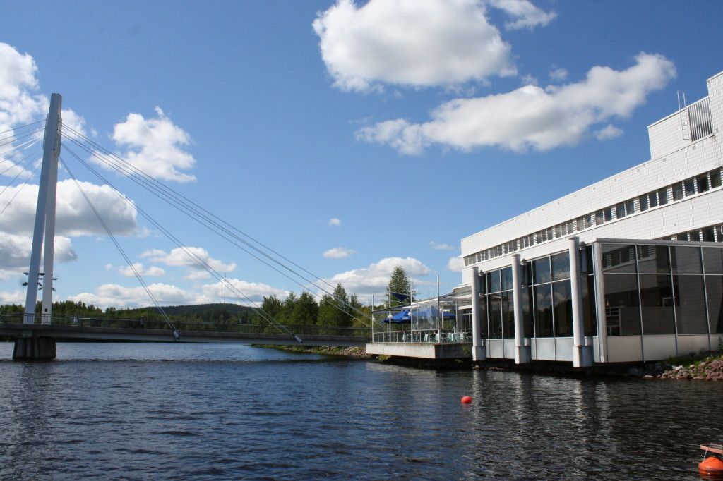 Un bâtiment moderne doté de grandes fenêtres et surmonté d’un pont en arrière-plan.