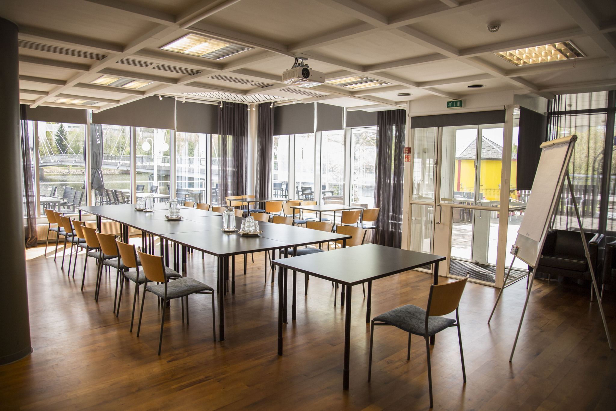 Un salón de conferencias con mesas y sillas grandes, un proyector y una pizarra.