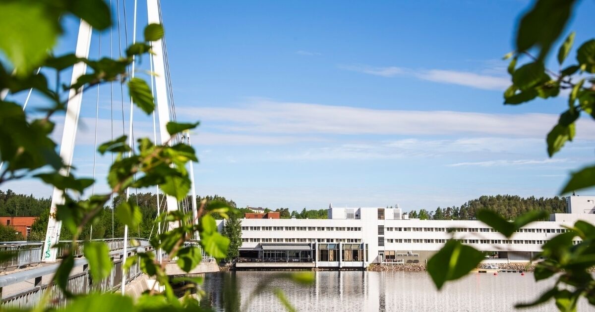Un edificio moderno con techo plano, ventanas amplias y un cuerpo de agua en primer plano.
