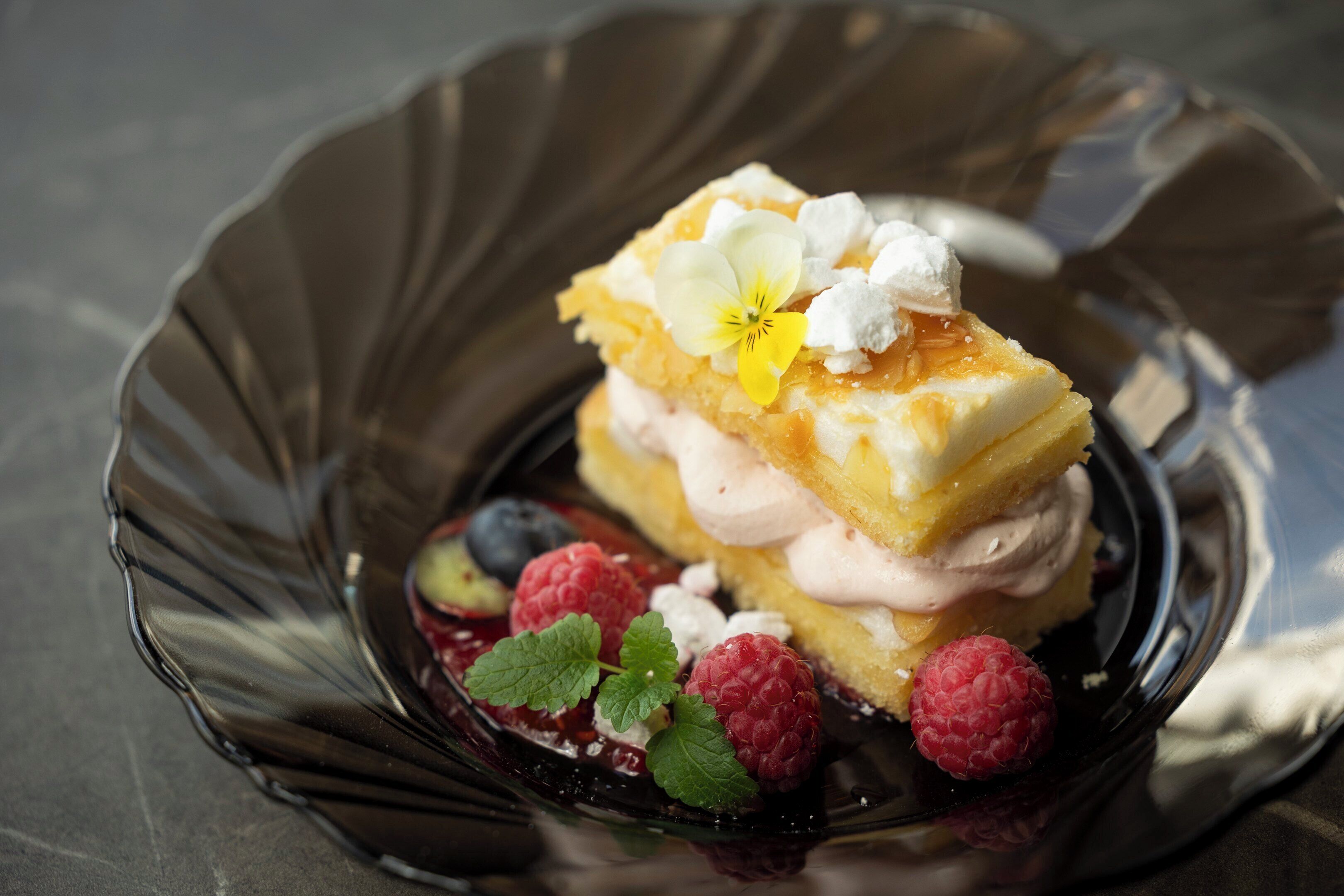 Uma sobremesa com frutas vermelhas e creme numa travessa de vidro.