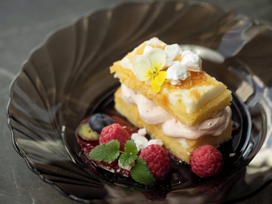 Un dessert aux fruits rouges et à la crème, servi dans une assiette en verre.