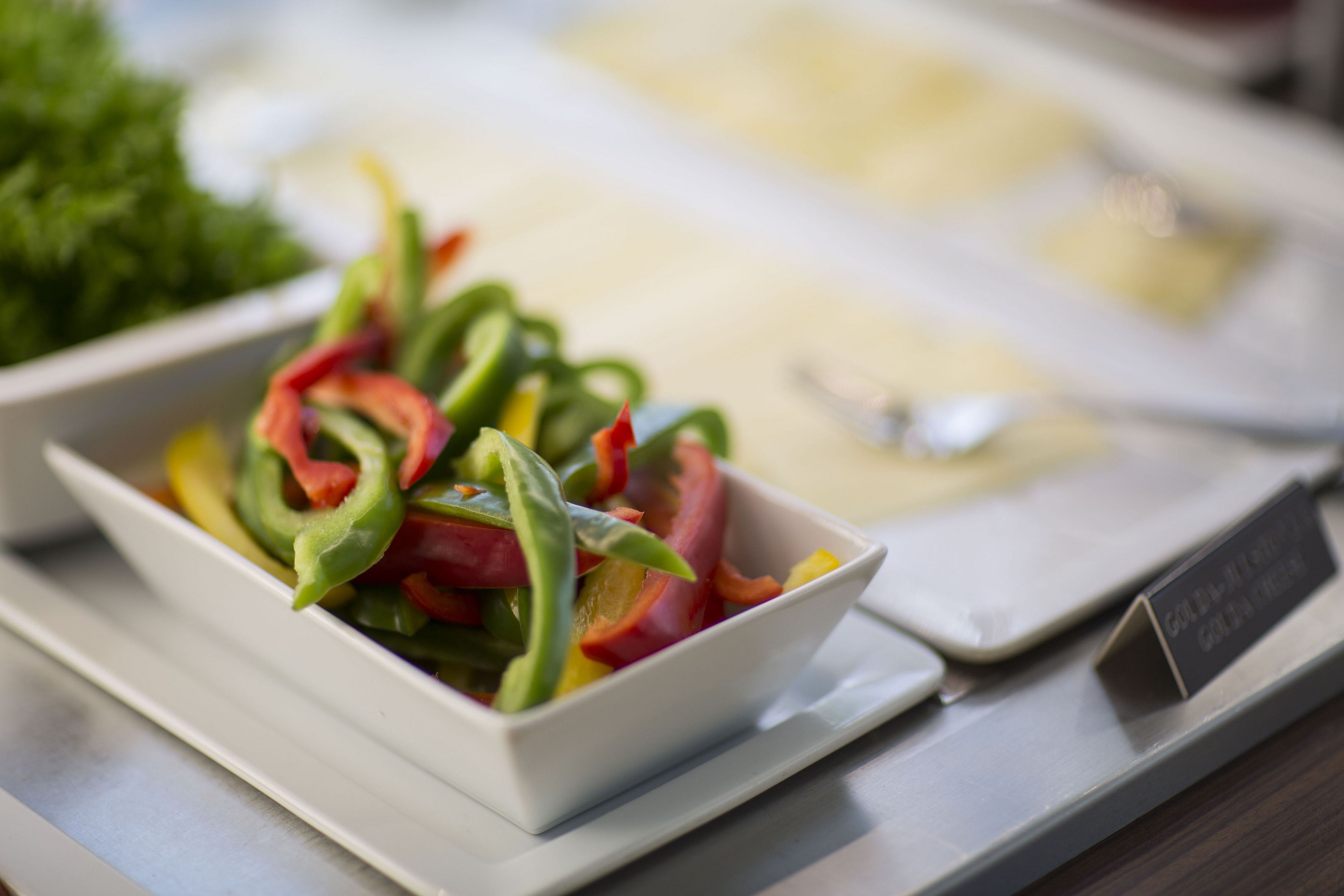 A white bowl filled with sliced bell peppers on a tray.