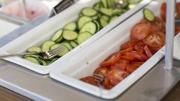 A buffet with trays of sliced cucumbers and tomatoes.
