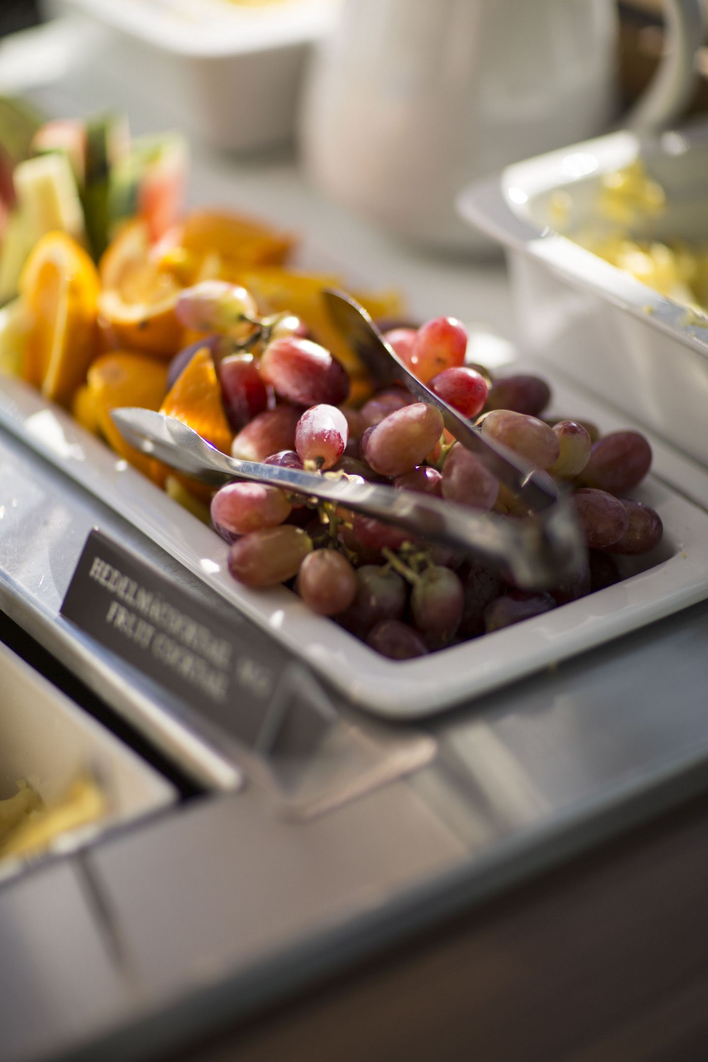 Une table de buffet proposant une variété de fruits, notamment des raisins, des oranges et des pommes.