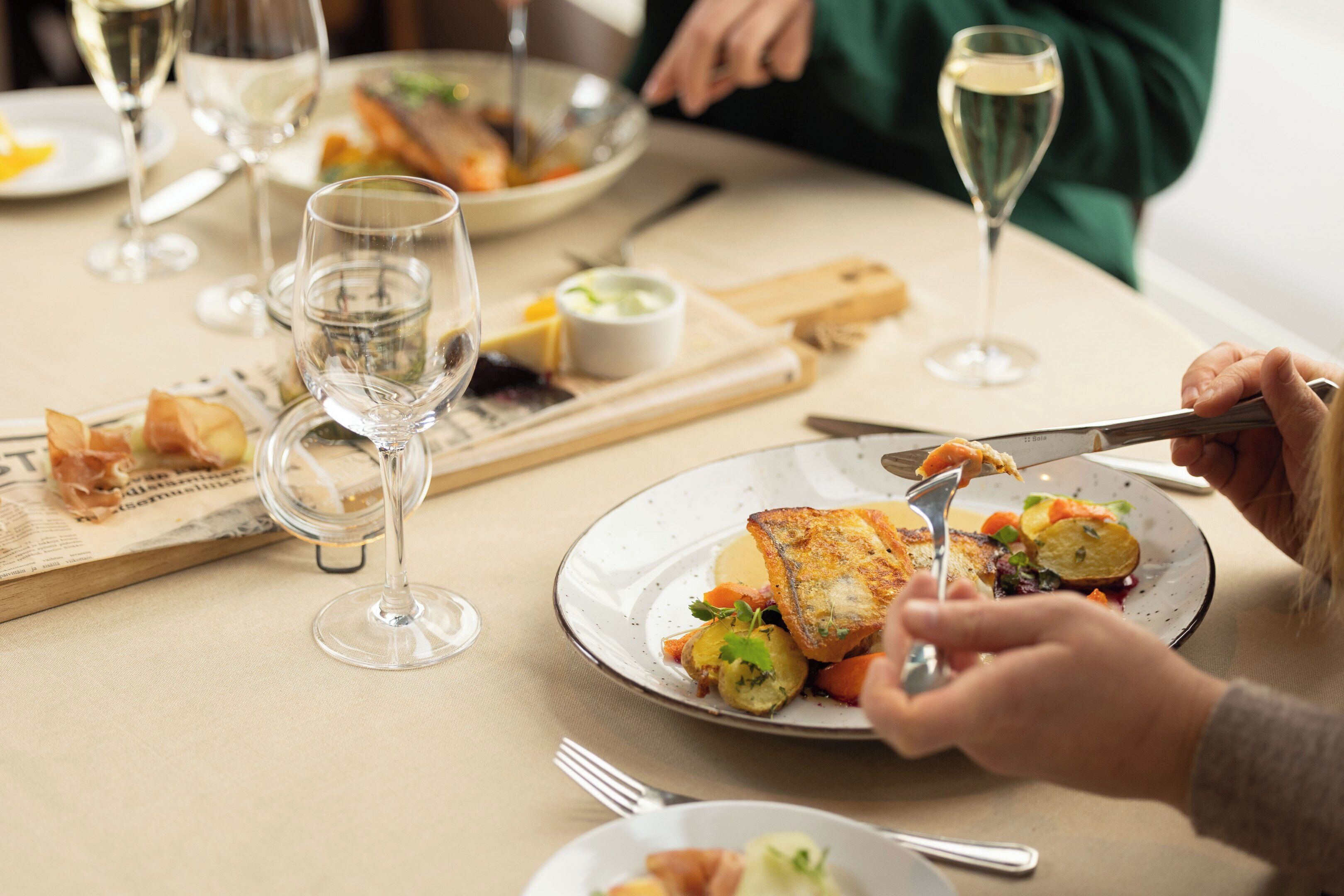 Een eettafel met borden eten, wijnkaraffen en bestek.