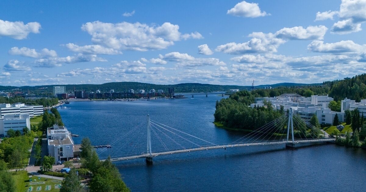 A cable-stayed bridge over a river with buildings on the banks.