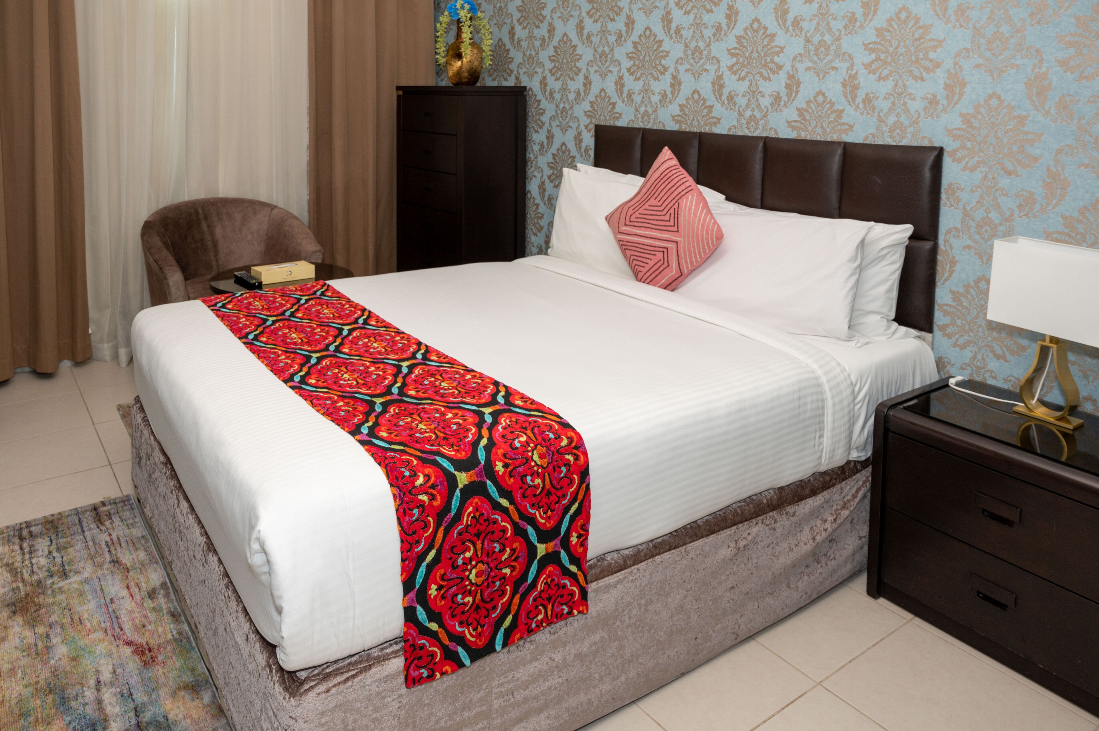 Una habitación de hotel con una cama grande, una mesita de noche, una silla y un escritorio.