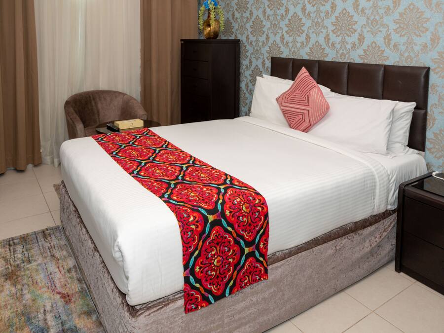 Una habitación de hotel con una cama grande, una mesita de noche, una silla y un escritorio.