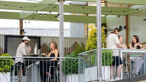 Un patio al aire libre con barandilla de metal, una mesa y sillas.