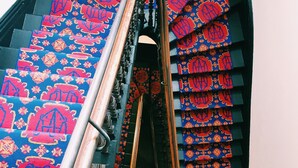 Una escalera con barandilla metálica y un suelo azul con diseños rojos.