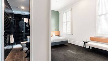 A modern bathroom with a black tiled shower, a toilet, and a sink.