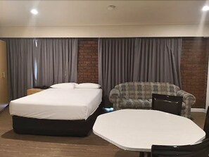 A hotel room with a bed, a sofa, and a small table. - Dandenong Motel (Dandenong)