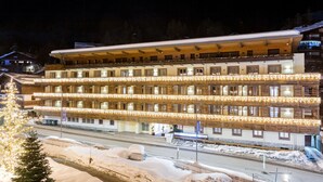 Un hotel de varios pisos con fachada de madera, múltiples balcones y una calle cubierta de nieve.