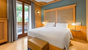 Un dormitorio de madera con una cama grande, un banco y vistas a un balcón.