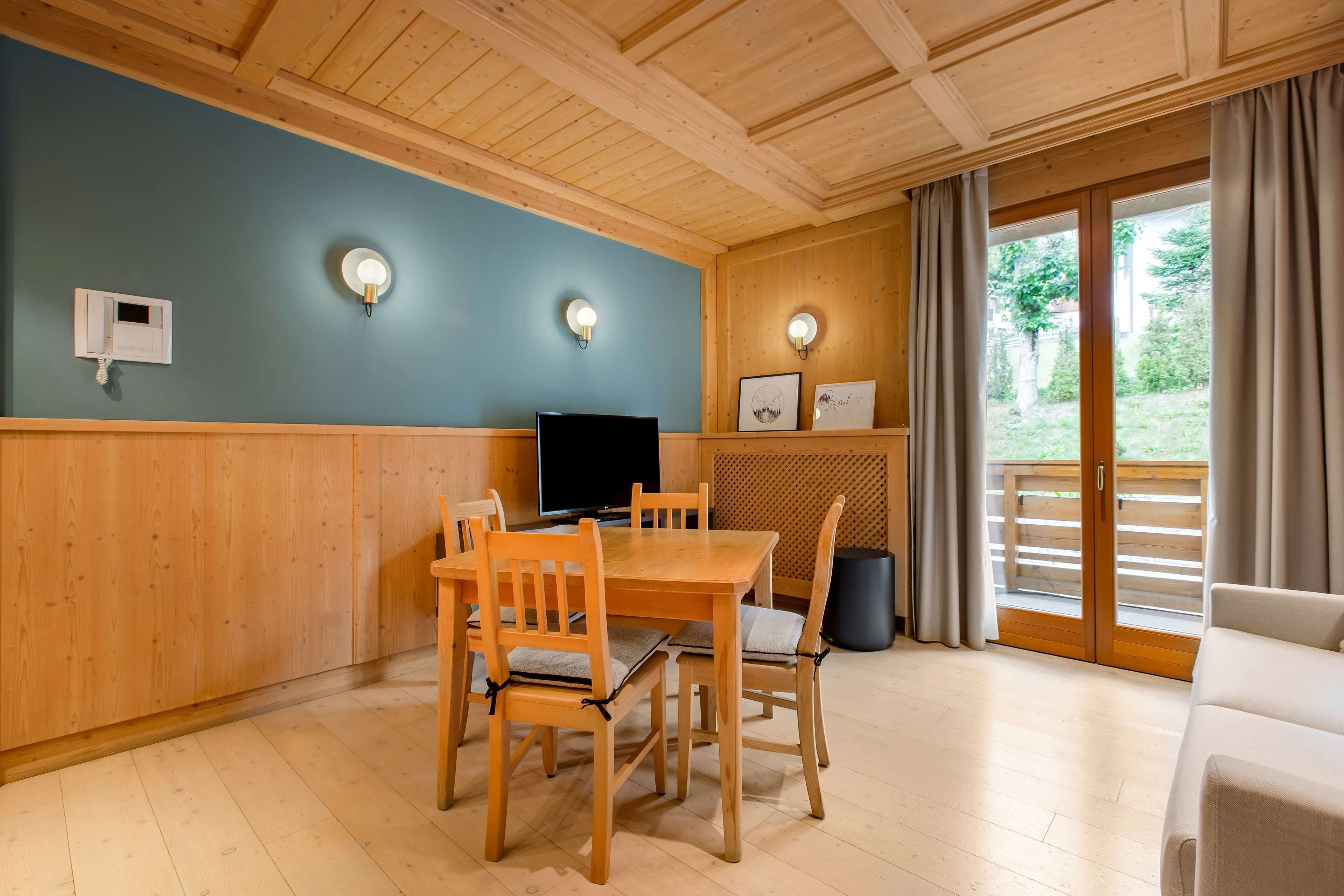 Una habitación con paneles de madera, una mesa de comedor, sillas, un televisor y un sofá.