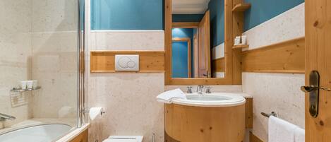 A bathroom with a bathtub, toilet, sink, and a mirror.