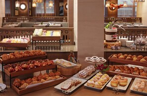 Un buffet proposant une variété de viennoiseries et de desserts, notamment des croissants, des pains au chocolat et d’autres produits de boulangerie.