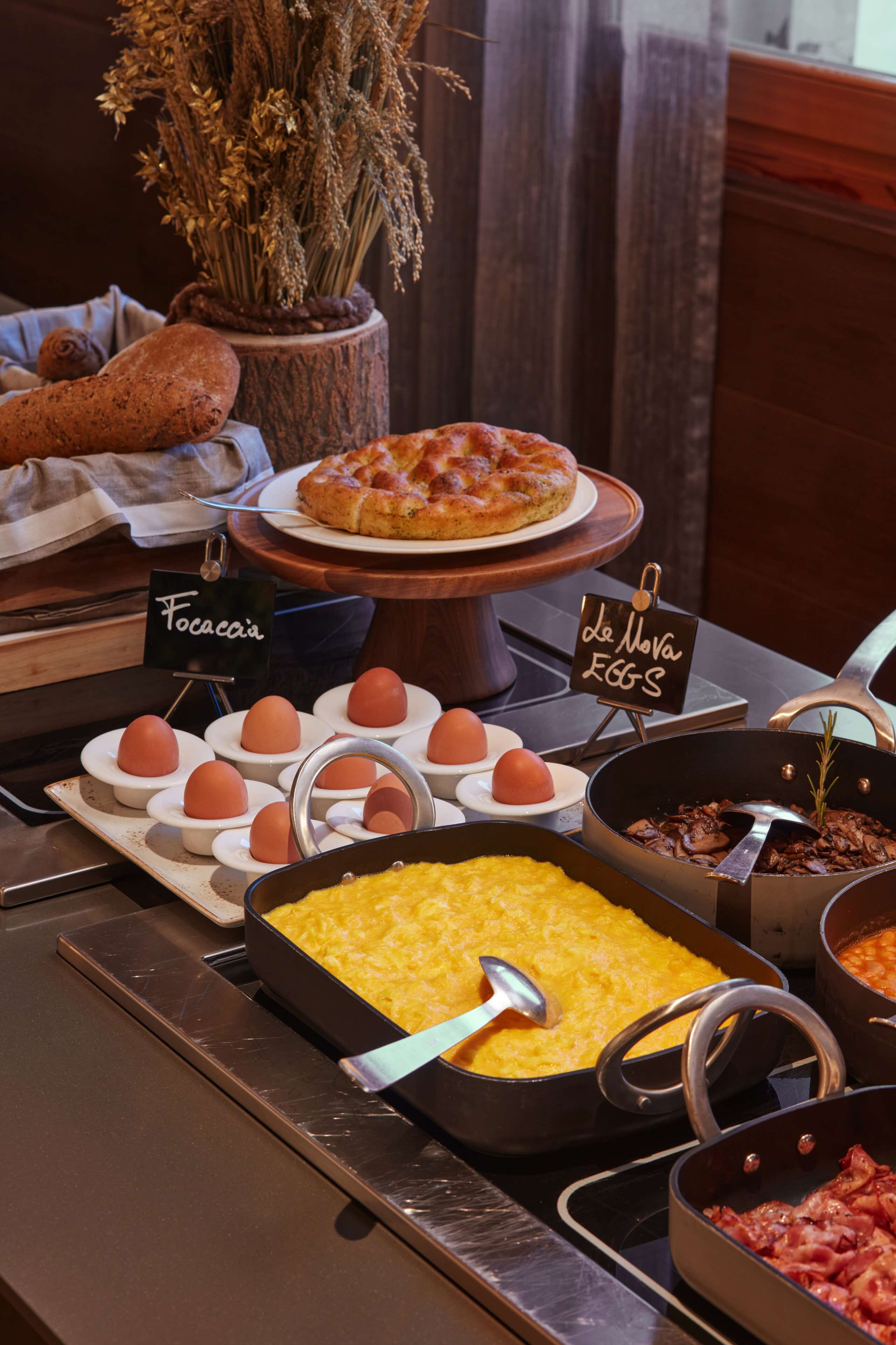 A buffet with various food items including eggs, a pizza, and a dish with yellow rice.